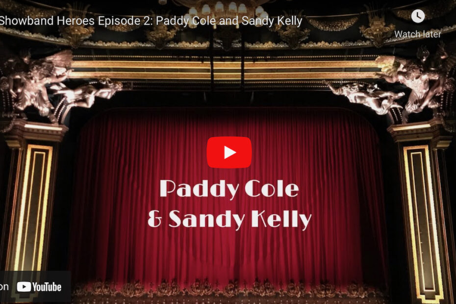 Photo of a stage with red velvet curtains, with the text Paddy Cole and Sandy Kelly superimposed under a YouTube play button